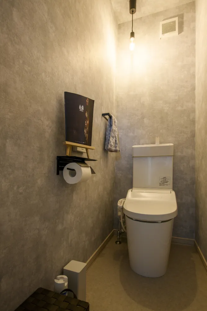グレーのクロスに温かみのあるペンダントライトが映える、シックなトイレ空間